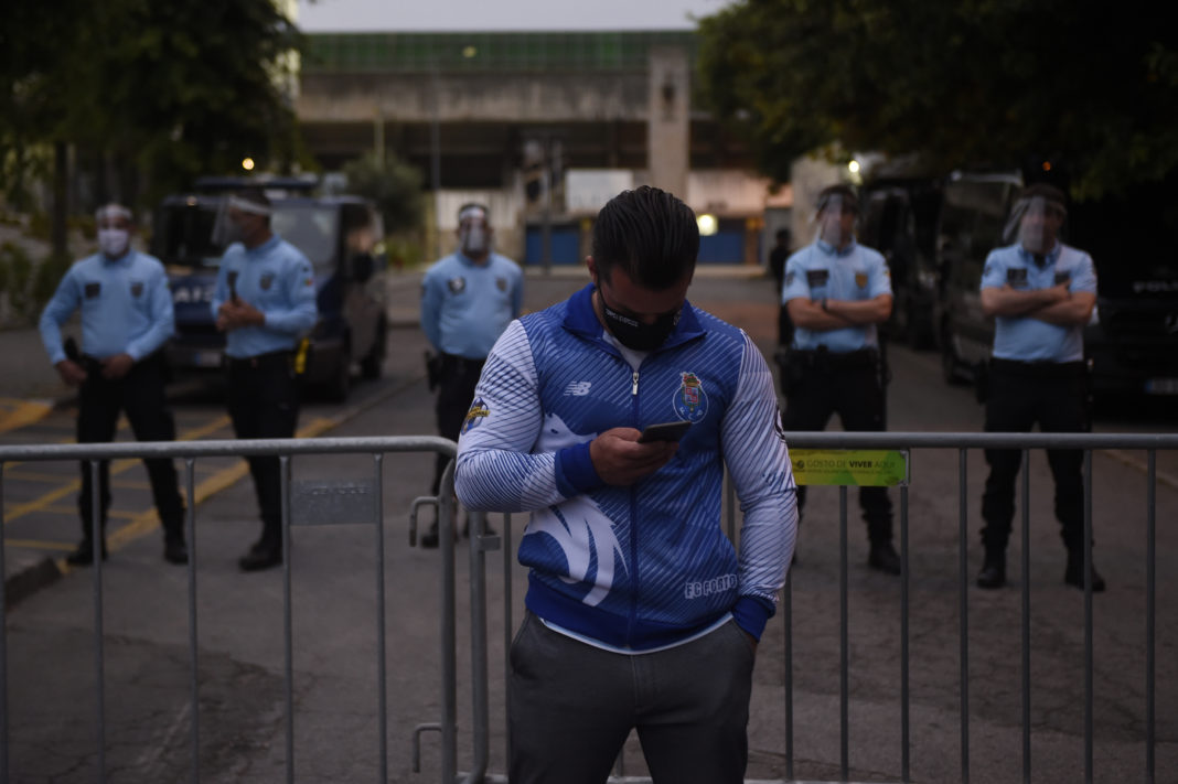 A FC Porto supporter stands in front of policemen outside the Municipal Stadium in Vila Nova de Famalicao on June 03, 2020 during the Portuguese league football match FC Famalicao against FC Porto. (Photo by MIGUEL RIOPA / AFP) (Photo by MIGUEL RIOPA/AFP via Getty Images)