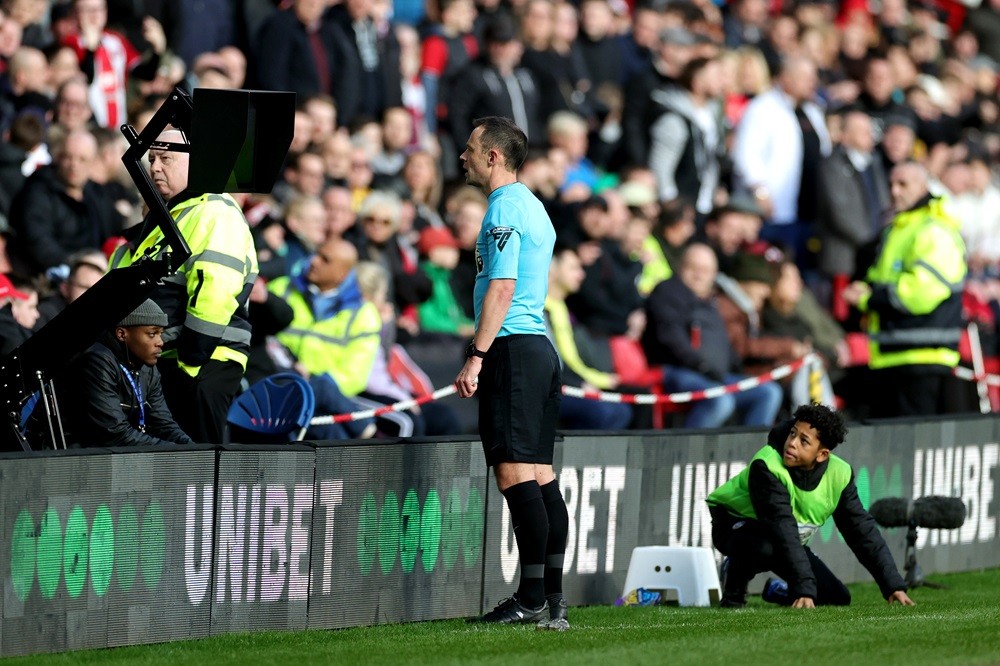 SHEFFIELD, ENGLAND: Referee Stuart Attwell checks the VAR screen for a red card for Mason Holgate of Sheffield United (not pictured), which was later given during the Premier League match between Sheffield United and Brighton & Hove Albion at Bramall Lane on February 18, 2024. (Photo by David Rogers/Getty Images)