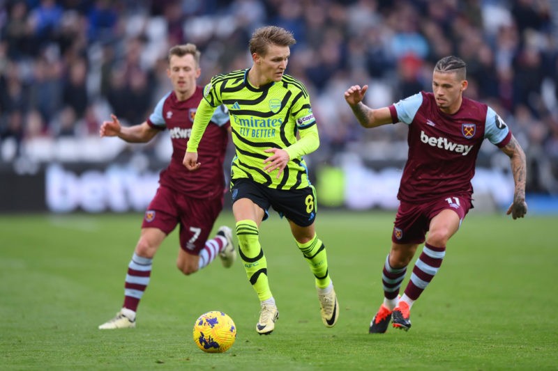 LONDON, ENGLAND - FEBRUARY 11: Martin Odegaard of Arsenal runs with the ball from Kalvin Phillips of West Ham United during the Premier League match between West Ham United and Arsenal FC at London Stadium on February 11, 2024 in London, England. (Photo by Justin Setterfield/Getty Images)