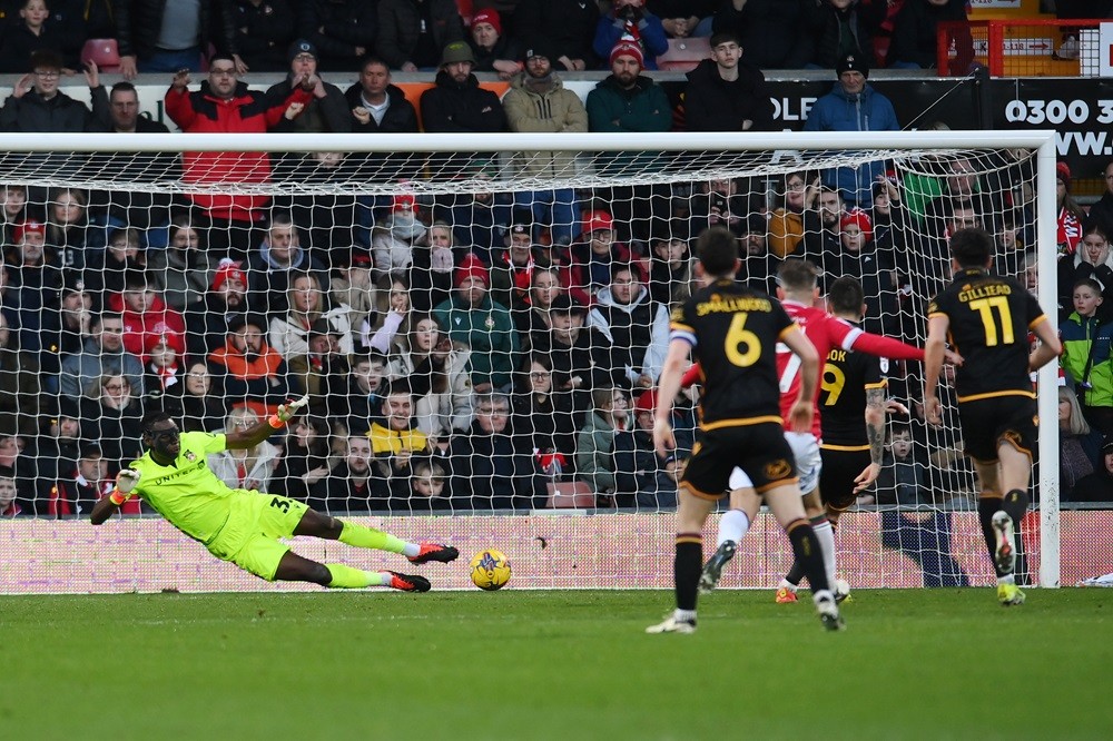 WREXHAM, WALES: Arthur Okonkwo of Wrexham saves a penalty from Andy Cook of Bradford City during the Sky Bet League Two match between Wrexham and Bradford City at Racecourse Ground on February 10, 2024. (Photo by Ben Roberts Photo/Getty Images)
