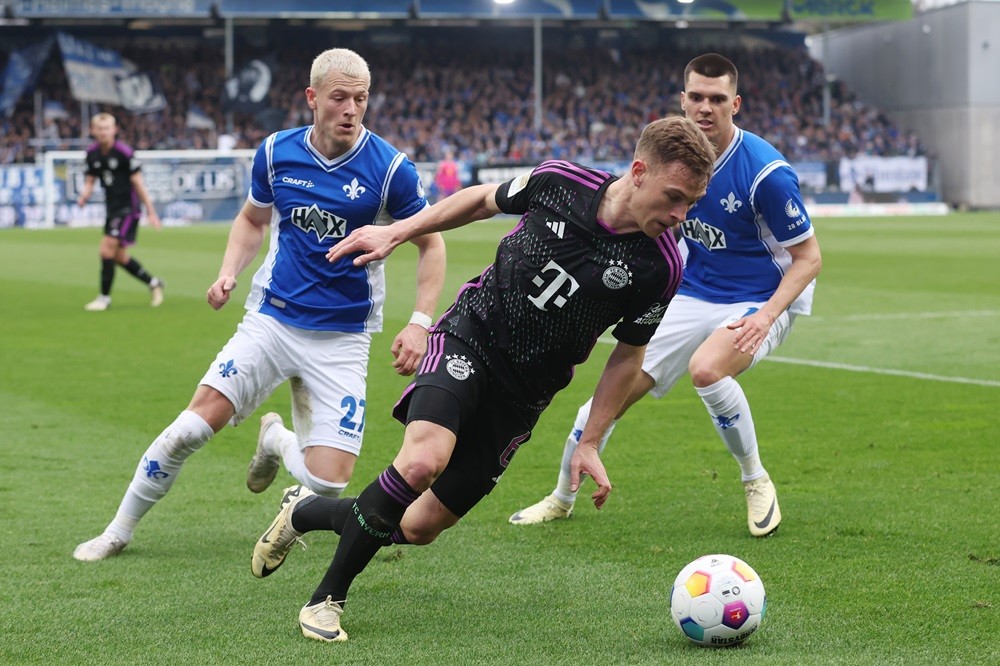 DARMSTADT, GERMANY: Joshua Kimmich of Bayern Muenchen is challenged by Tim Skarke and Mathias Honsak of Darmstadt during the Bundesliga match between SV Darmstadt 98 and FC Bayern München at Merck-Stadion am Böllenfalltor on March 16, 2024. (Photo by Alex Grimm/Getty Images)
