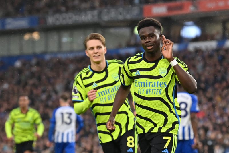 Arsenal's English midfielder #07 Bukayo Saka (R) celebrates after scoring the opening goal from the penalty spot during the English Premier League football match between Brighton and Hove Albion and Arsenal at the American Express Community Stadium in Brighton, southern England on April 6, 2024. (Photo by GLYN KIRK/AFP via Getty Images)