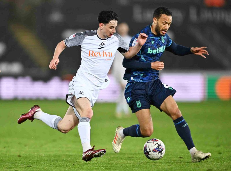 SWANSEA, WALES - APRIL 10: Charlie Patino of Swansea City battles for possession with Lewis Baker of Stoke City during the Sky Bet Championship match between Swansea City and Stoke City at Liberty Stadium on April 10, 2024 in Swansea, Wales. (Photo by Dan Mullan/Getty Images)