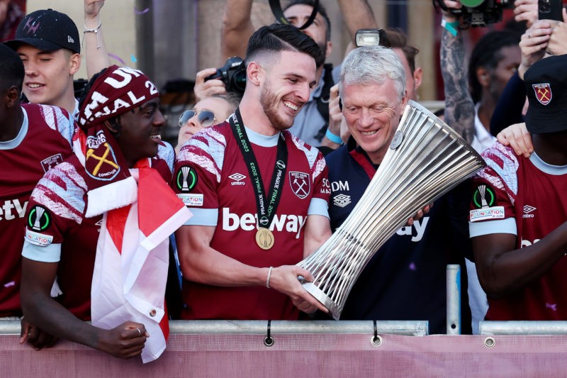 LONDON, ENGLAND - JUNE 08: Declan Rice of West Ham United admires the Europa Conference League trophy with David Moyes, Manager of West Ham United, as players of West Ham United celebrate on a balcony whilst looking out over a crowd of fans during the West Ham United trophy parade on June 08, 2023 in London, England. West Ham defeated ACF Fiorentina in the Europa Conference League Final on June 7th. (Photo by Eddie Keogh/Getty Images)