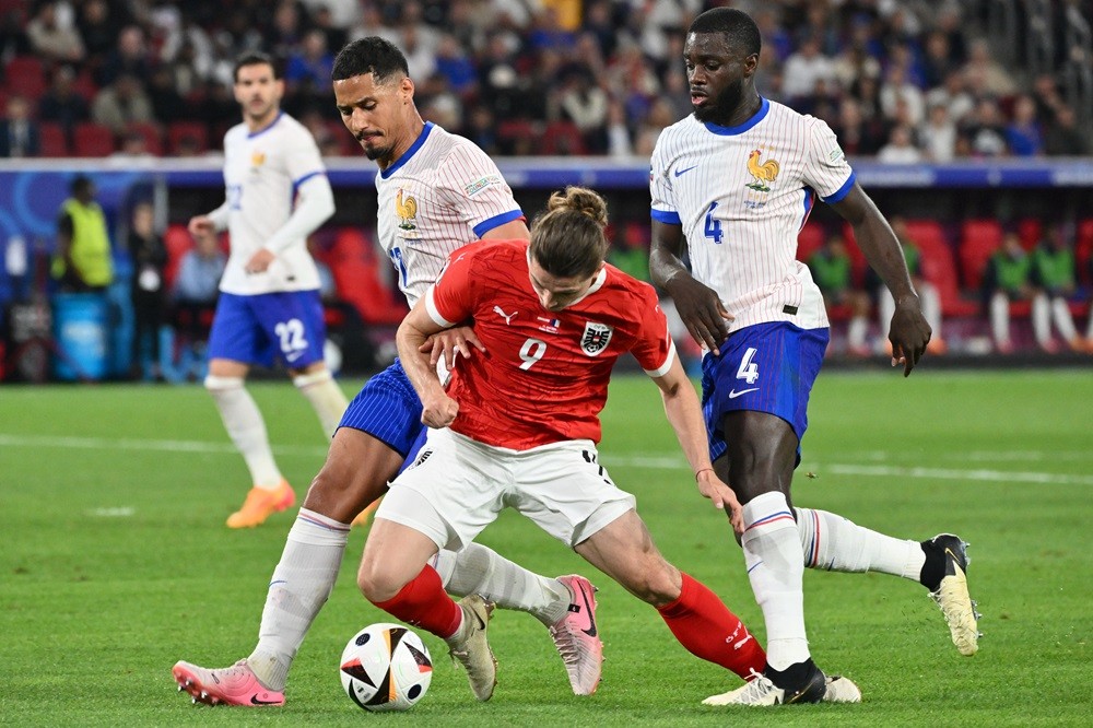France's William Saliba and Dayot Upamecano fight for the ball with Austria's Marcel Sabitzer during the UEFA Euro 2024 Group D football match between Austria and France at the Duesseldorf Arena in Duesseldorf on June 17, 2024. (Photo by ALBERTO PIZZOLI/AFP via Getty Images)