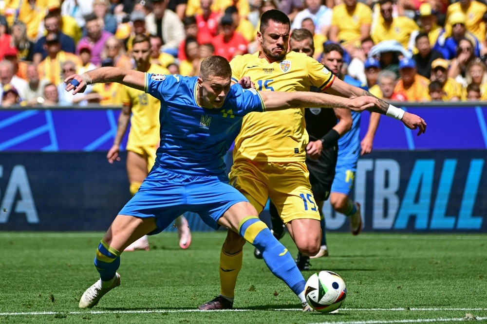 Ukraine's Artem Dovbyk (L) challenges Romania's Andrei Burca during the UEFA Euro 2024 Group E football match between Romania and Ukraine at the Munich Football Arena in Munich on June 17, 2024. (Photo by TOBIAS SCHWARZ/AFP via Getty Images)