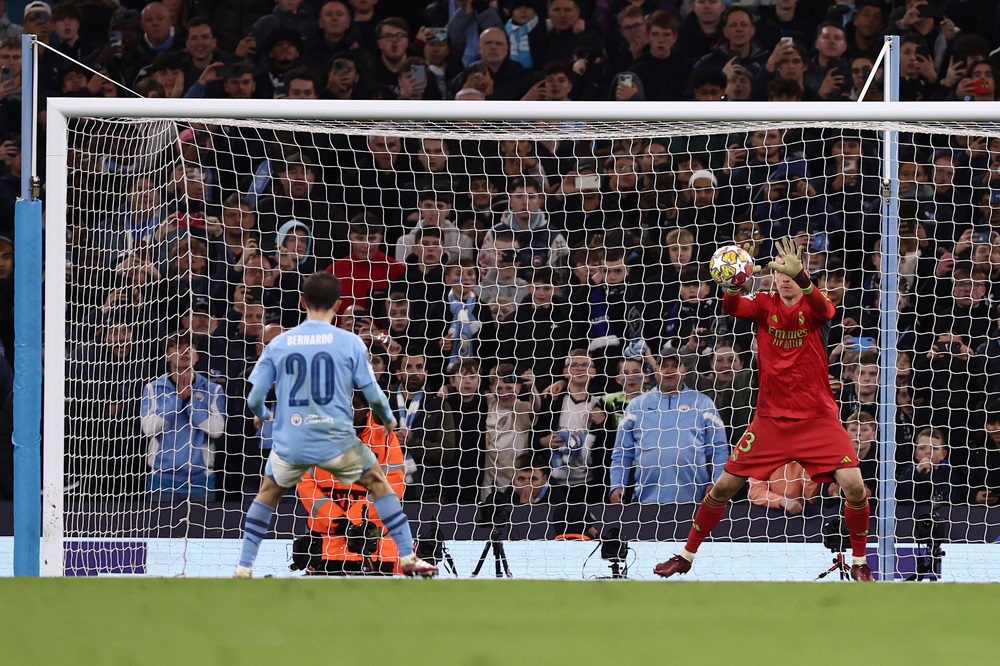 MANCHESTER, ENGLAND: Andriy Lunin of Real Madrid saves the second penalty from Bernardo Silva of Manchester City in the penalty shoot out during the UEFA Champions League quarter-final second leg match between Manchester City and Real Madrid CF at Etihad Stadium on April 17, 2024. (Photo by Naomi Baker/Getty Images)