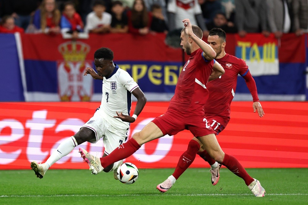 GELSENKIRCHEN, GERMANY: Bukayo Saka of England crosses the ball whilst under pressure from Strahinja Pavlovic and Filip Kostic of Serbia during the UEFA EURO 2024 group stage match between Serbia and England at Arena AufSchalke on June 16, 2024. (Photo by Kevin C. Cox/Getty Images)
