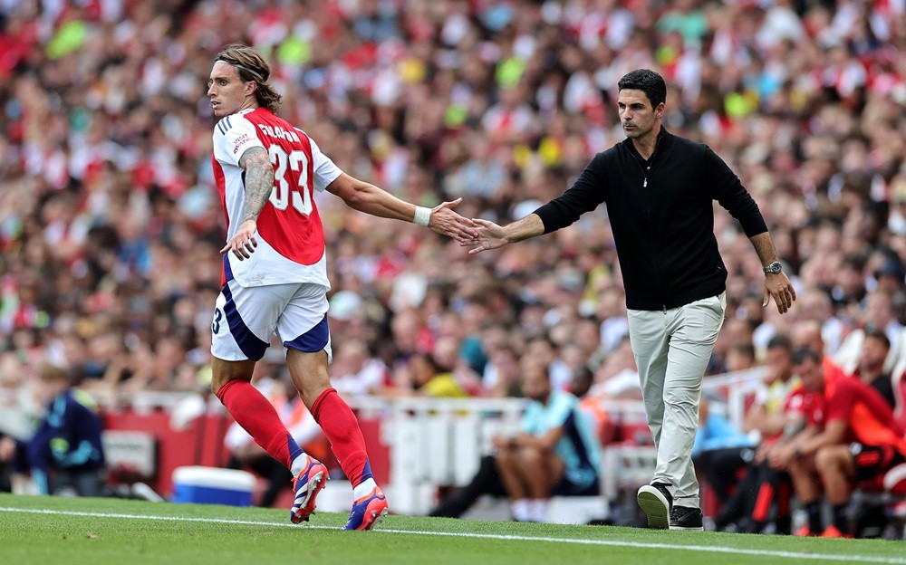 LONDON, ENGLAND: Riccardo Calafiori of Arsenal touches hands with Arsenal manager Mikel Arteta during the pre-season friendly match between Arsenal and Olympique Lyonnais at the Emirates Stadium on August 11, 2024. (Photo by David Rogers/Getty Images)