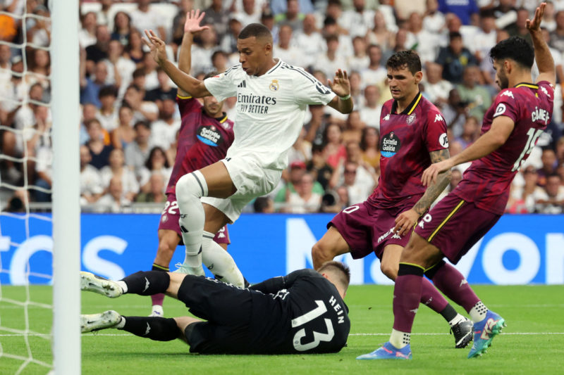 Real Madrid's French forward #09 Kylian Mbappe (L) and Real Valladolid's Estonian goalkeeper #13 Karl Jakob Hein vie for the ball during the Spanish league football match between Real Madrid CF and Real Valladolid FC at the Santiago Bernabeu stadium in Madrid on August 25, 2024. (Photo by PIERRE-PHILIPPE MARCOU/AFP via Getty Images)