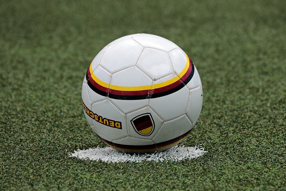 a white football with yellow red and black accents on a penalty spot