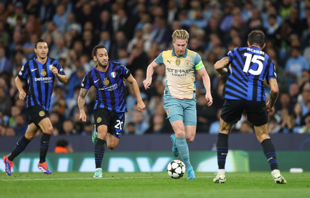 MANCHESTER, ENGLAND - SEPTEMBER 18: Kevin De Bruyne of Manchester City runs with the ball under pressure from Hakan Calhanoglu and Francesco Acerbi of FC Internazionale during the UEFA Champions League 2024/25 League Phase MD1 match between Manchester City and FC Internazionale Milano at City of Manchester Stadium on September 18, 2024 in Manchester, England. (Photo by Carl Recine/Getty Images)