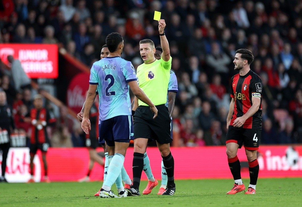 BOURNEMOUTH, ENGLAND: Match Referee, Robert Jones shows a yellow card to William Saliba of Arsenal during the Premier League match between AFC Bournemouth and Arsenal FC at Vitality Stadium on October 19, 2024. (Photo by Michael Steele/Getty Images)