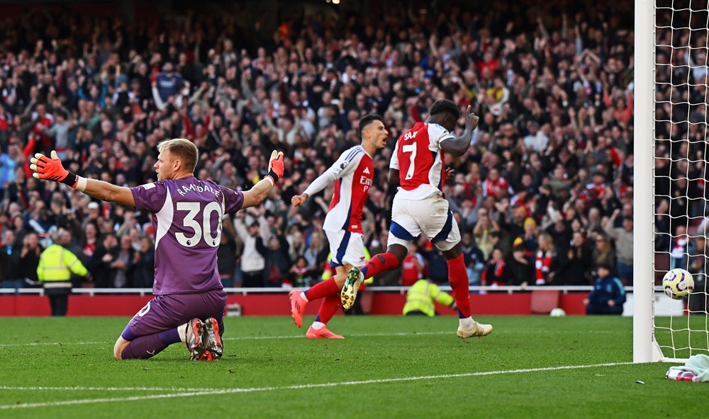 LONDON, ENGLAND: Bukayo Saka of Arsenal scores his team's third goal past Aaron Ramsdale of Southampton during the Premier League match between Arsenal FC and Southampton FC at Emirates Stadium on October 05, 2024. (Photo by Shaun Botterill/Getty Images)